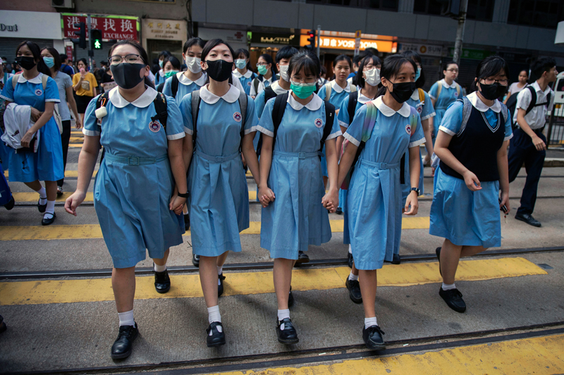 Students cross a road as they head to school after participating in a joint 'school human chain rally' in Hong Kong on September 12, 2019. Hong Kong's secondary schools have become the latest ideological battleground for pro-democracy protesters with